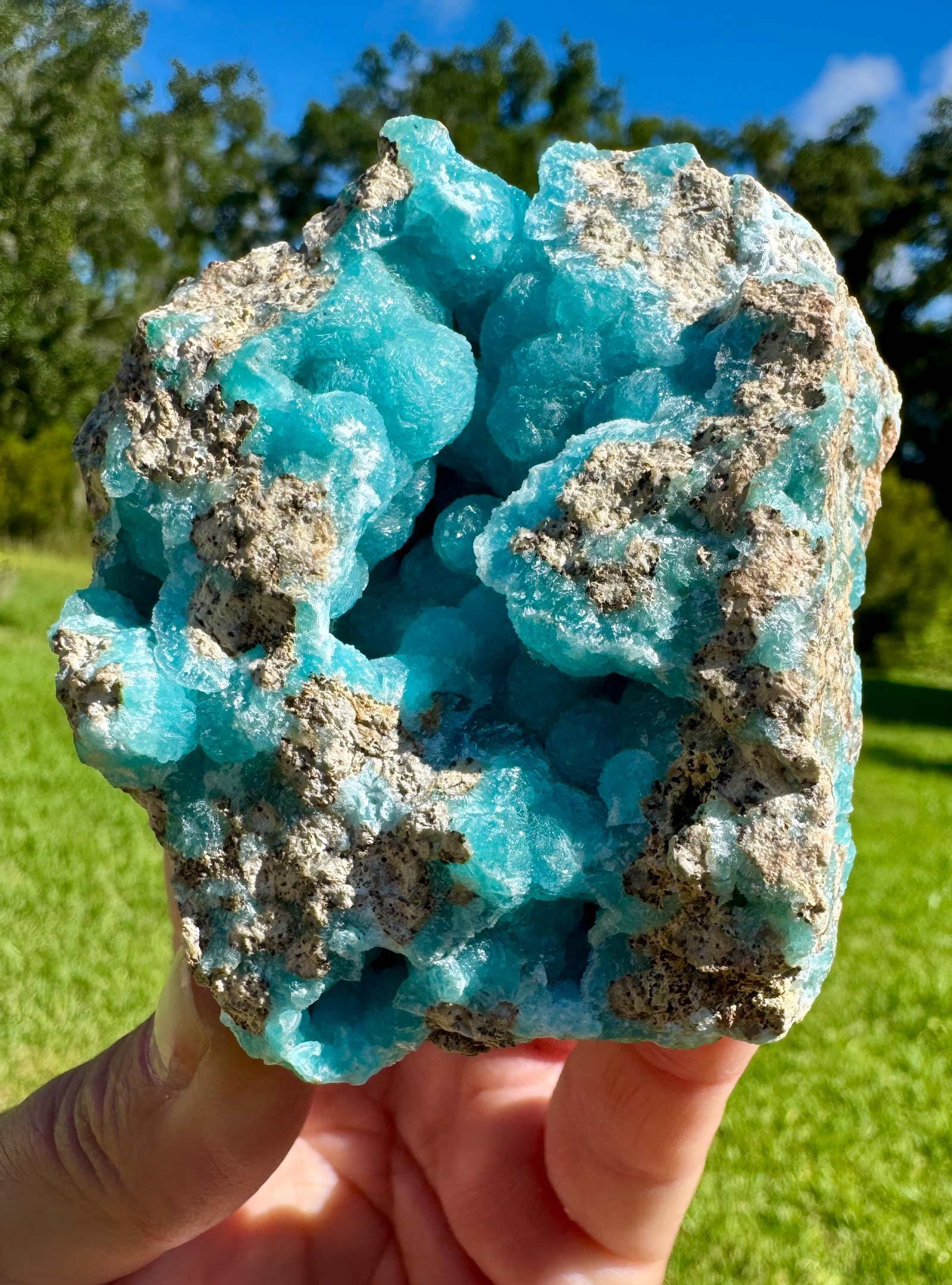 Blue hemimorphite specimen held in sunlight